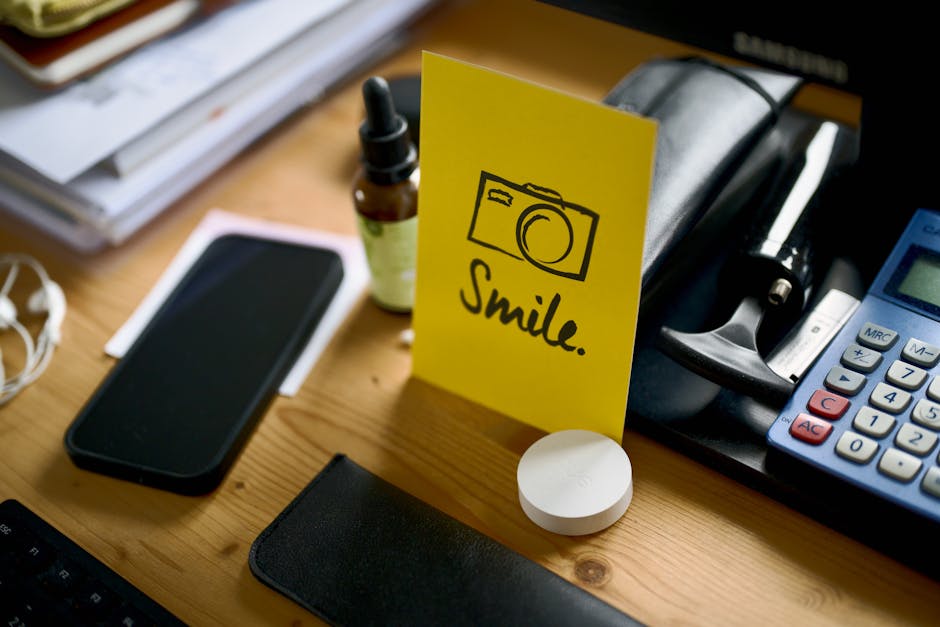 Ein Schreibtisch mit Smartphone, Taschenrechner und einer Motivationskarte mit der Aufschrift „Lächeln“.